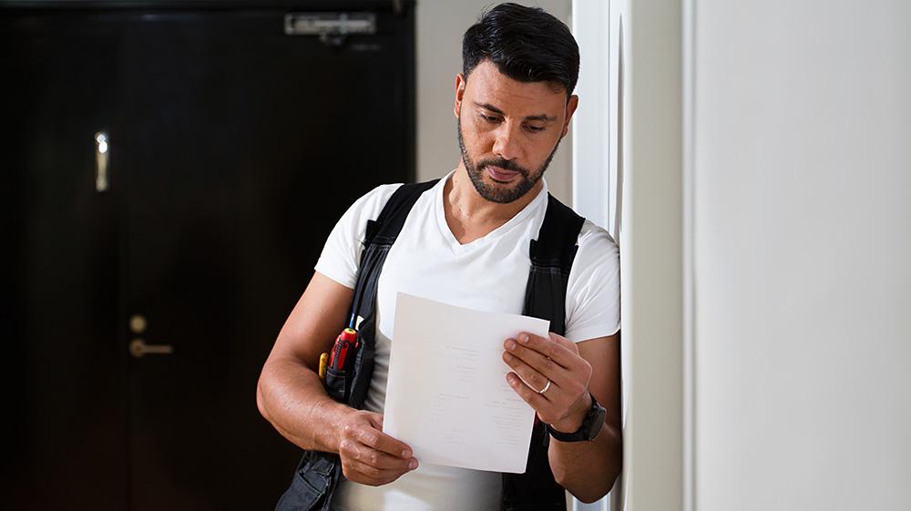 A man who works as a property caretaker reads his shift list.