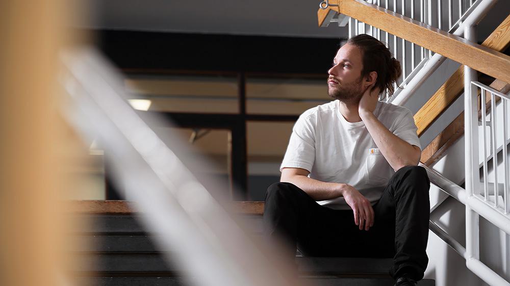 A young man is sitting inside the school on the stairs.